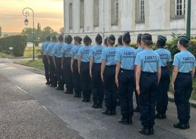 Groupe de cadets de la gendarmerie alignés en rang devant un bâtiment.