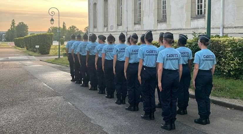 Formation des cadets de la gendarmerie Groupe de cadets de la gendarmerie alignés en rang devant un bâtiment.