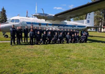 Groupe de cadets de la gendarmerie posant devant un avion exposé en extérieur.